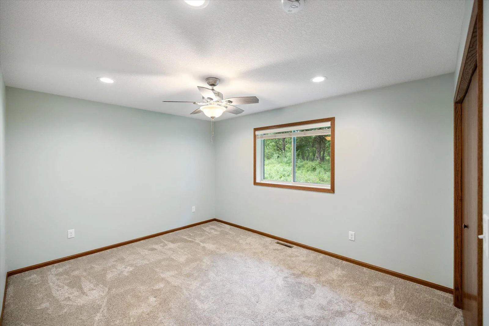 Another view of the primary bedroom in the main level with a large window that overlooks the private backyard.