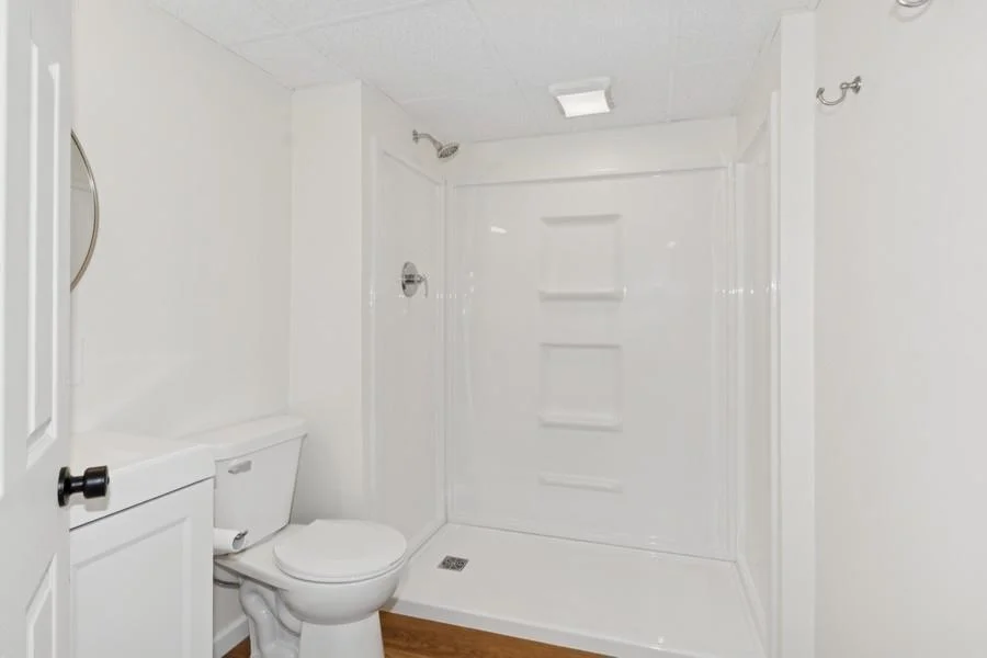 Remodeled lower level bathroom features a new shower stall, vanity and flooring.