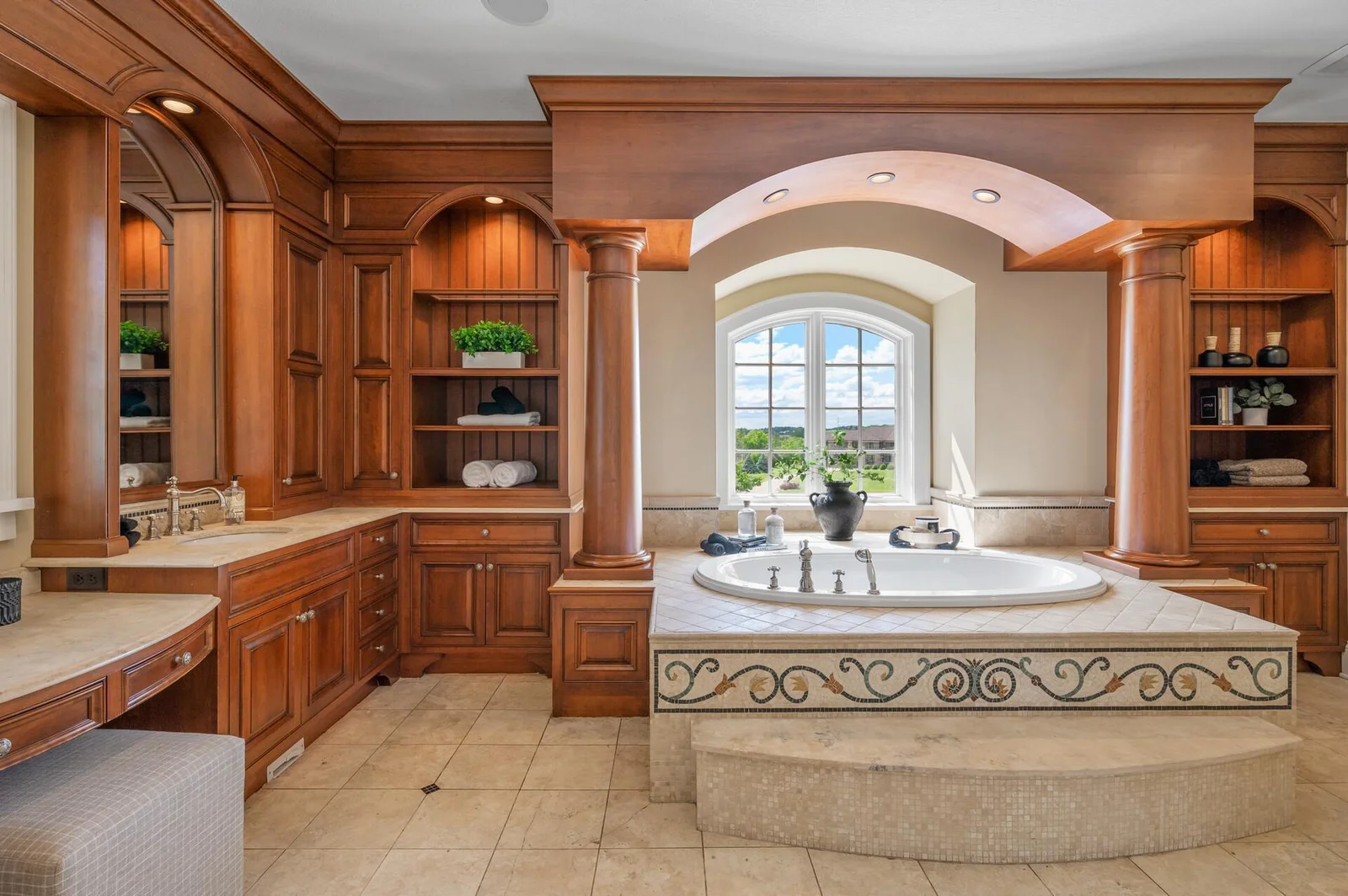 Impressive architectural columns frame the luxurious soaking tub and complement the arched window, adding unique character to the primary bathroom.
