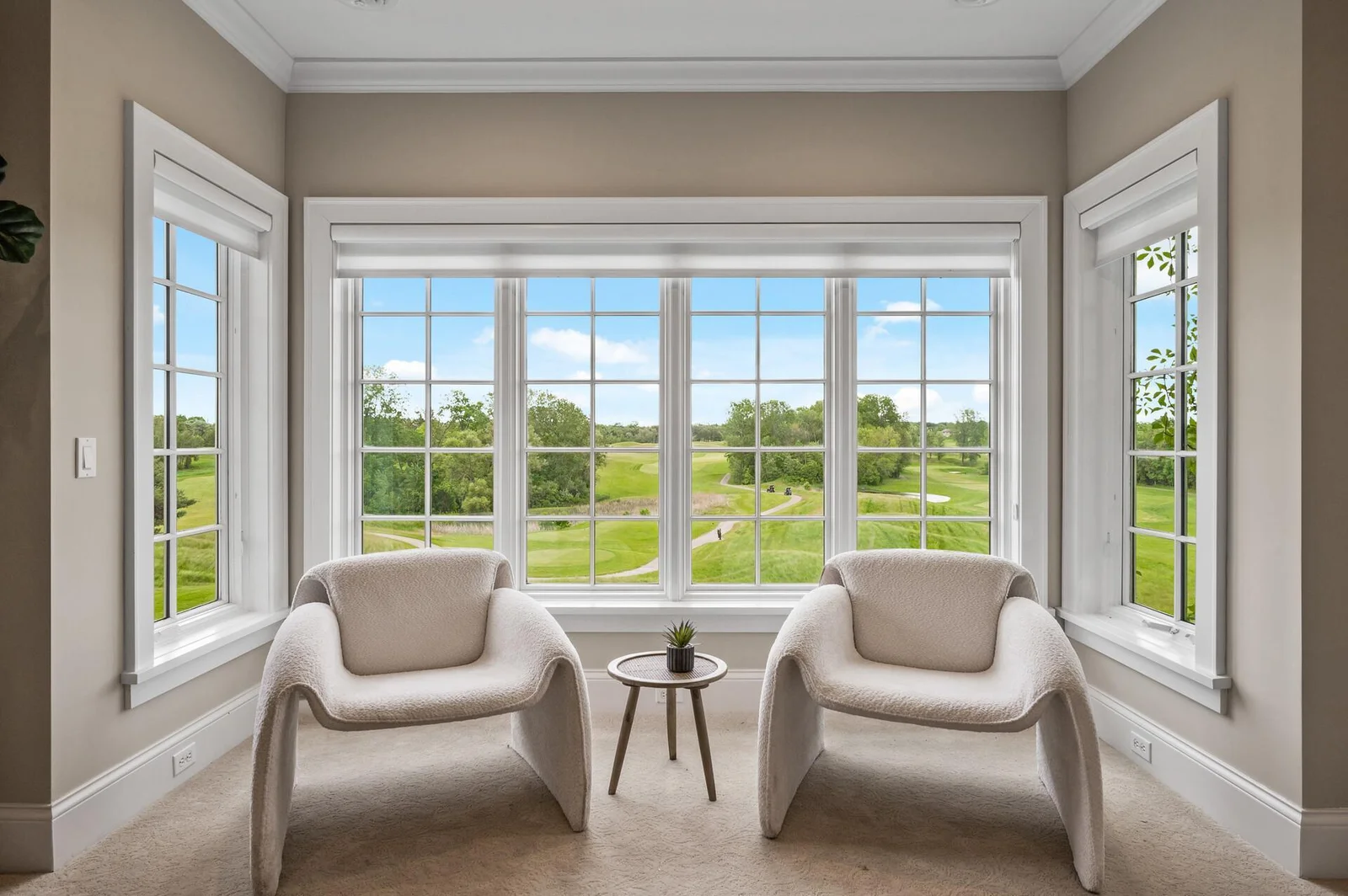 The primary suite sitting area offers an immersive view of the golf course.