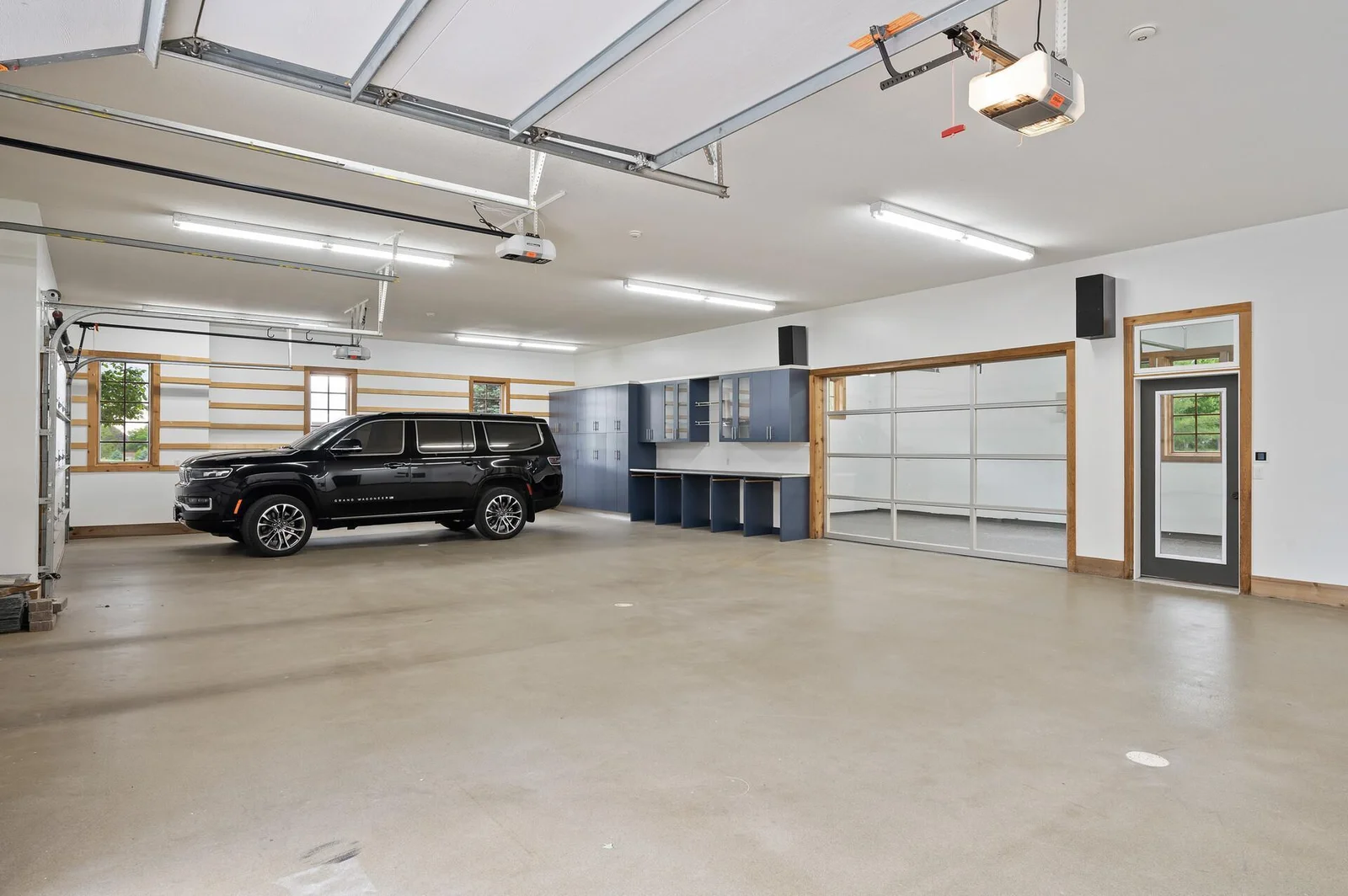 This 6-car garage offers ample space for vehicles, storage, and even a workshop area, enhanced by built-in cabinets.