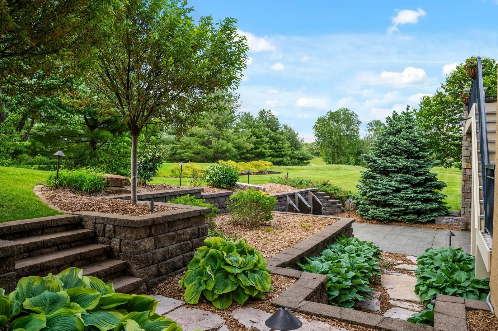 Tiered gardens and charming stone pathways enhance the beauty of the backyard landscape.