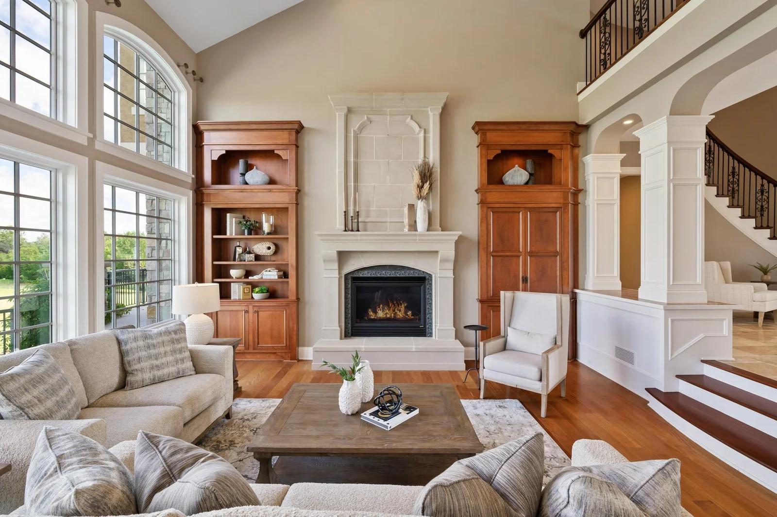 The soaring windows, elegant fireplace, and open two-story design create a dramatic yet welcoming living space.