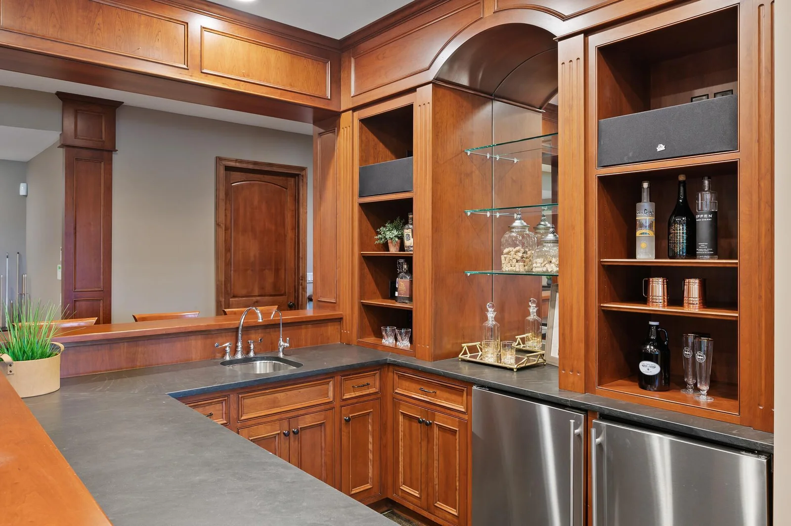 Beautiful wood cabinetry and stylish countertops of this custom bar add a touch of elegance to the lower level entertainment space.