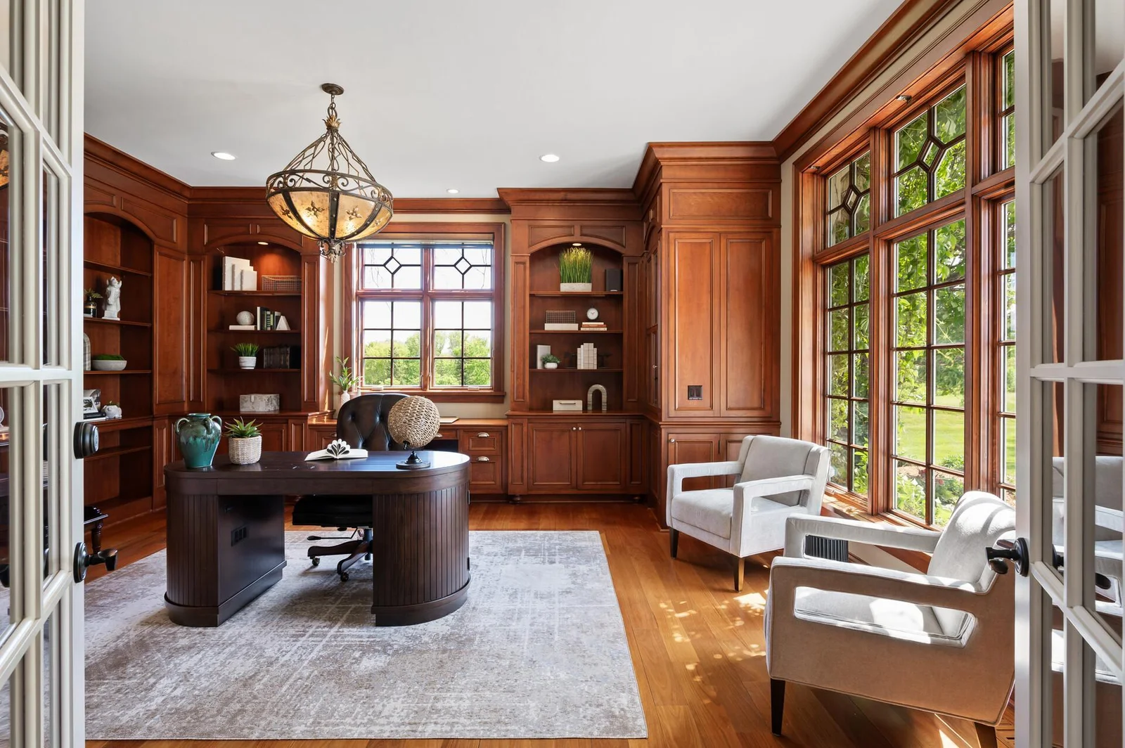 Sophisticated office with rich wood trim, comfortable seating, and ample natural light.