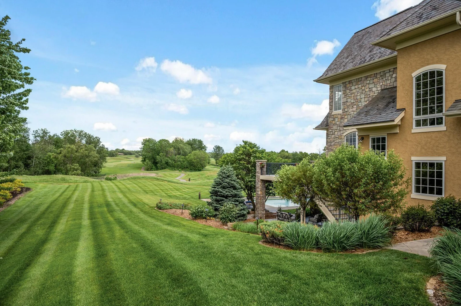 The beautifully landscaped backyard blends seamlessly with the surrounding greenery, offering golf course views.