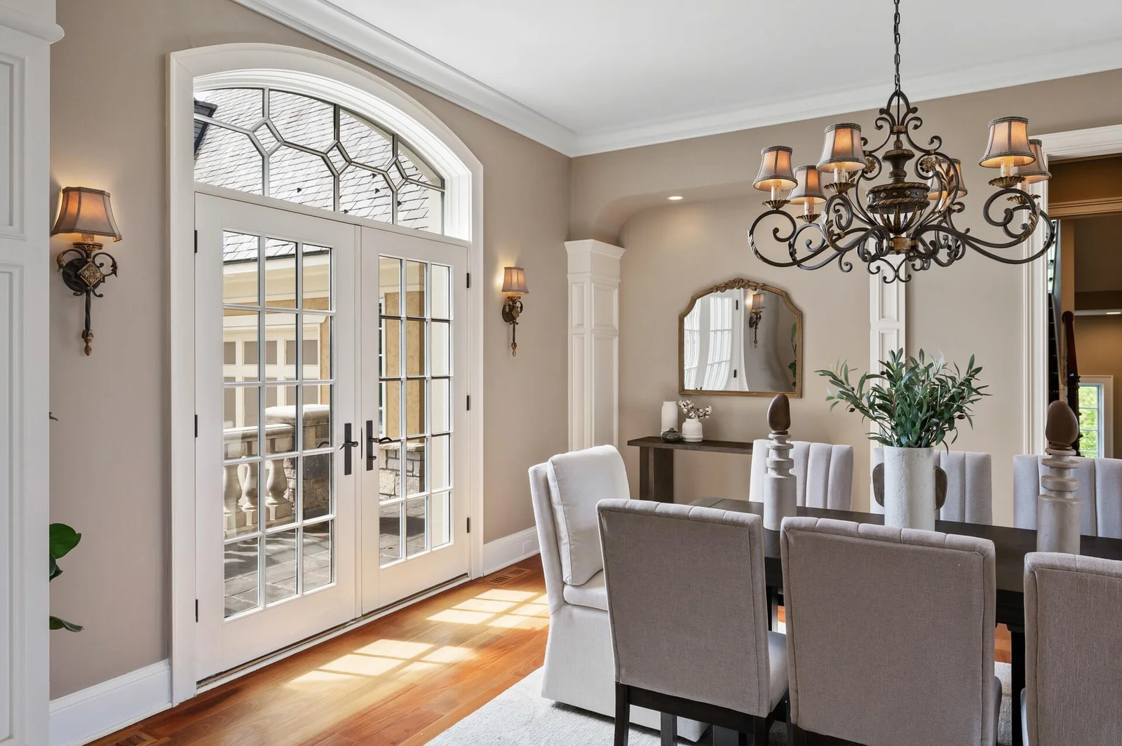 Sunlight streams through the elegant French doors, illuminating the dining room.
