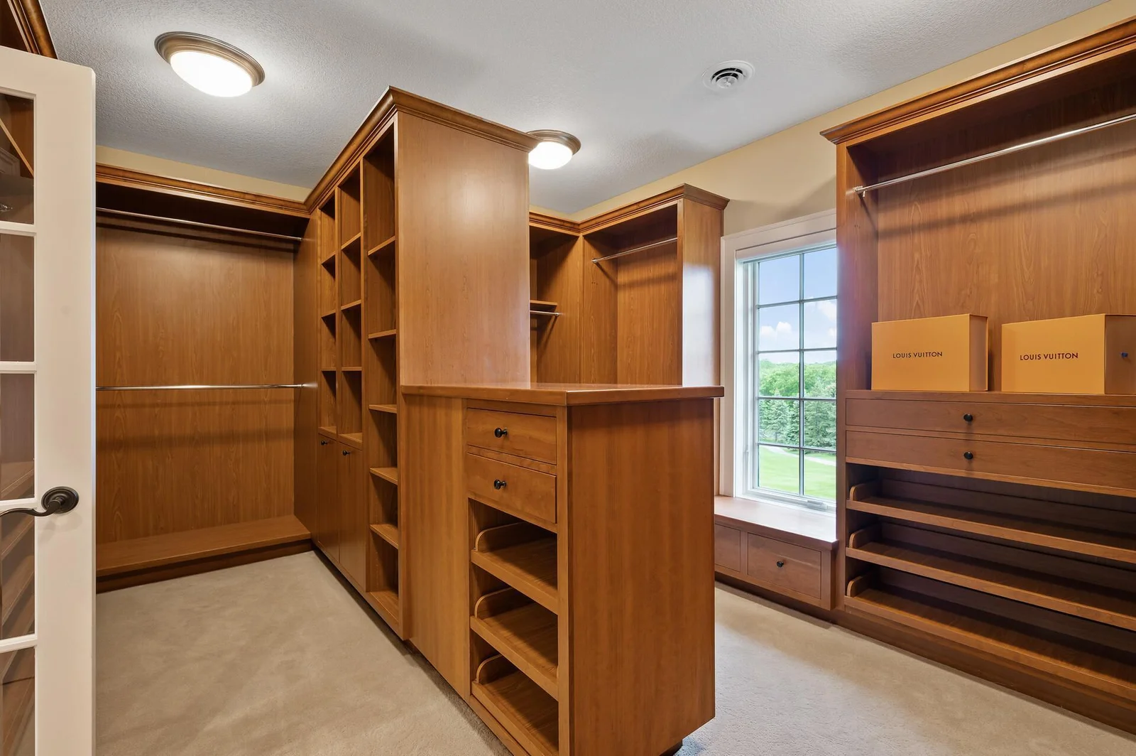 Exceptional custom wood shelving, drawers, and hanging space provide unparalleled organization in this large walk-in closet.
