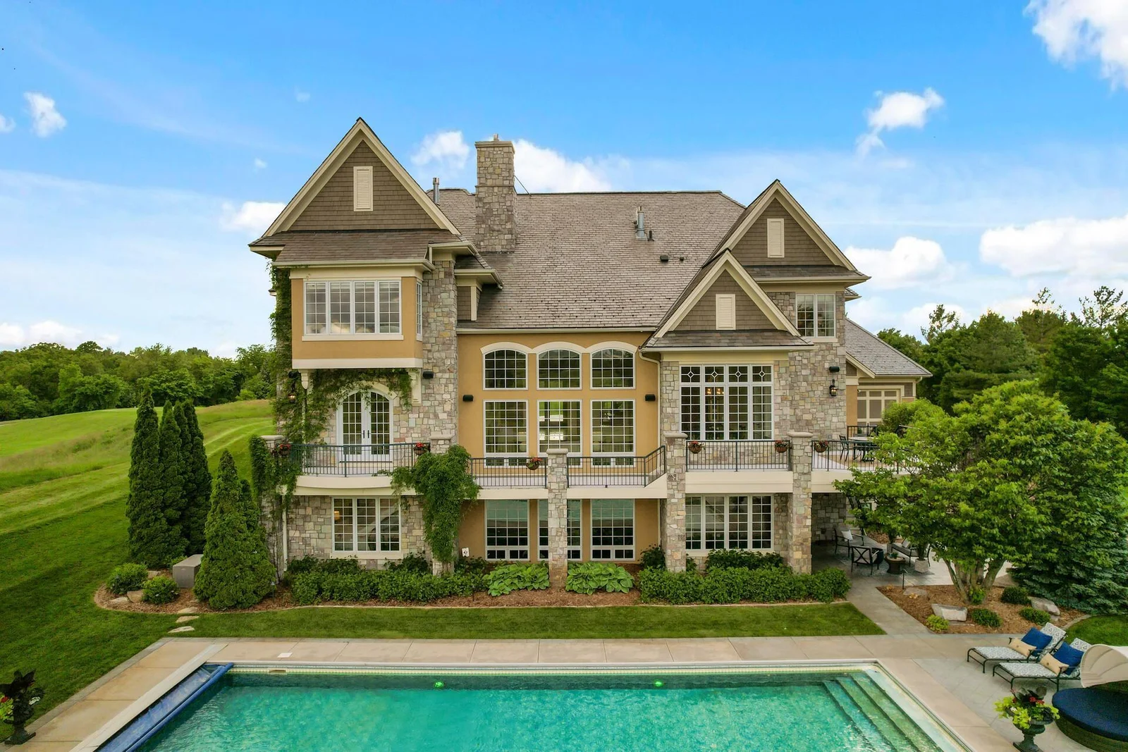 Magnificent rear of the home to the inviting pool and expansive lawn.