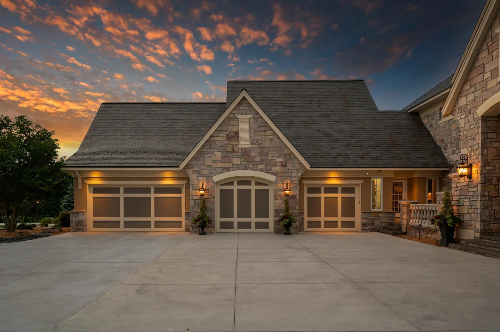 A spacious, beautifully designed 4-car garage featuring stone accents, arched detailing, and elegant carriage-style doors—offering both functionality and curb appeal.