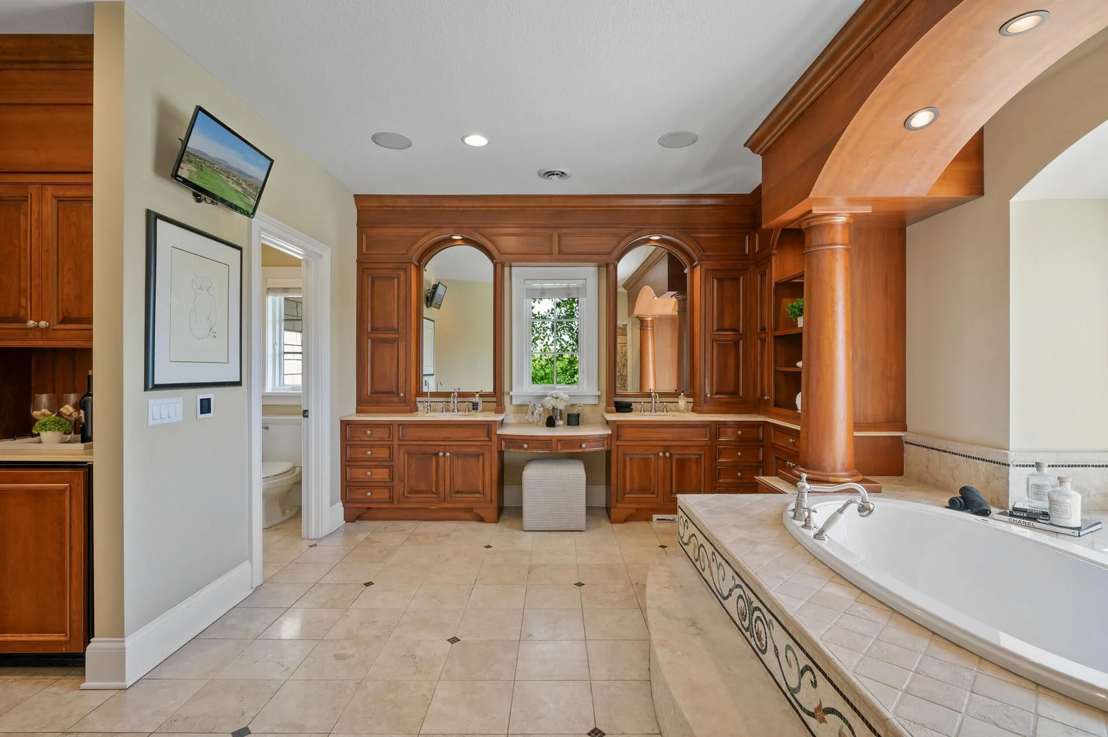 Enjoy the convenience of dual vanities and a dedicated makeup station in this expansive and luxurious bathroom.