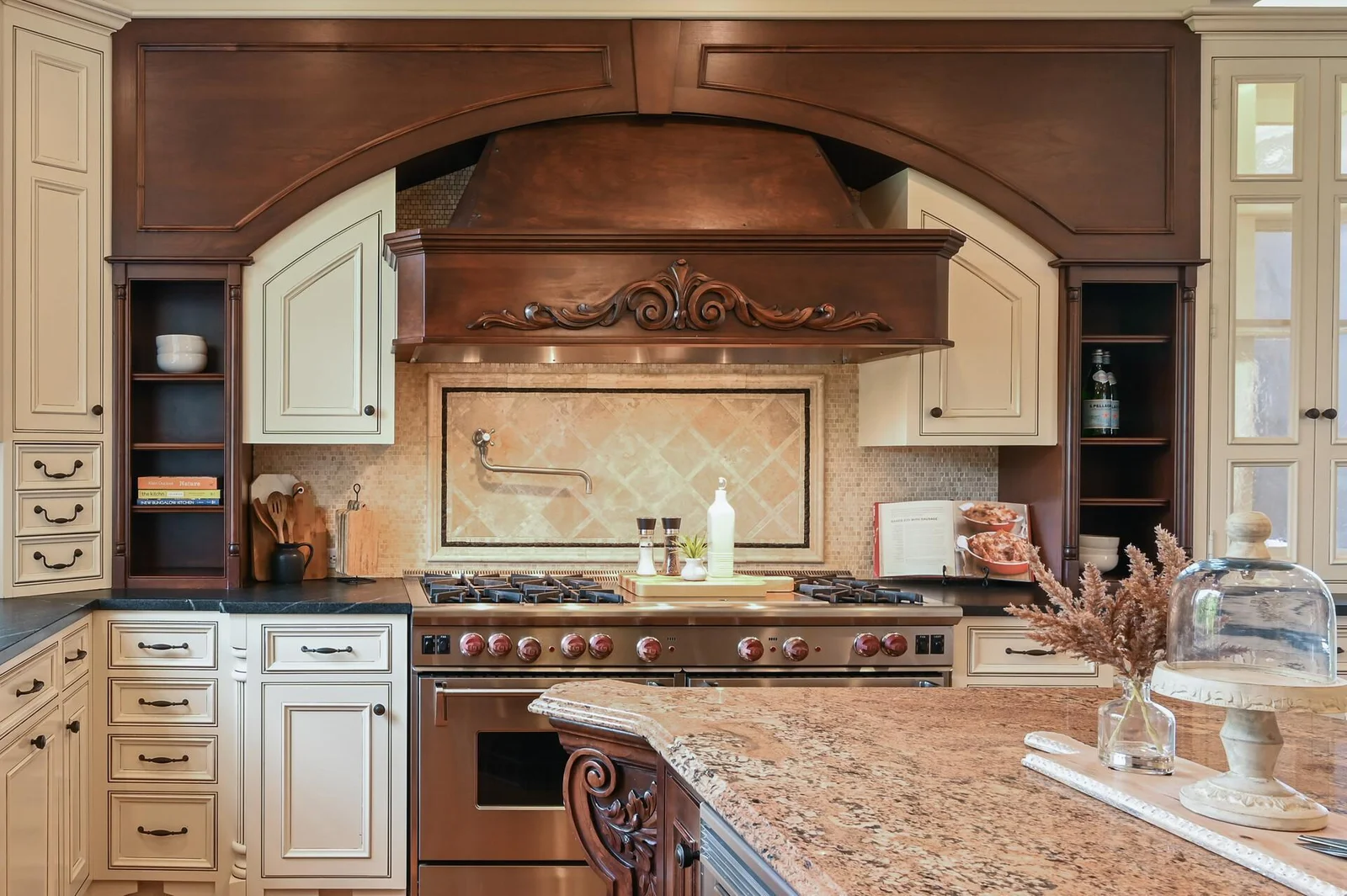 The elegant design of the kitchen is highlighted by the professional Wolf range and its ornate custom vent hood.