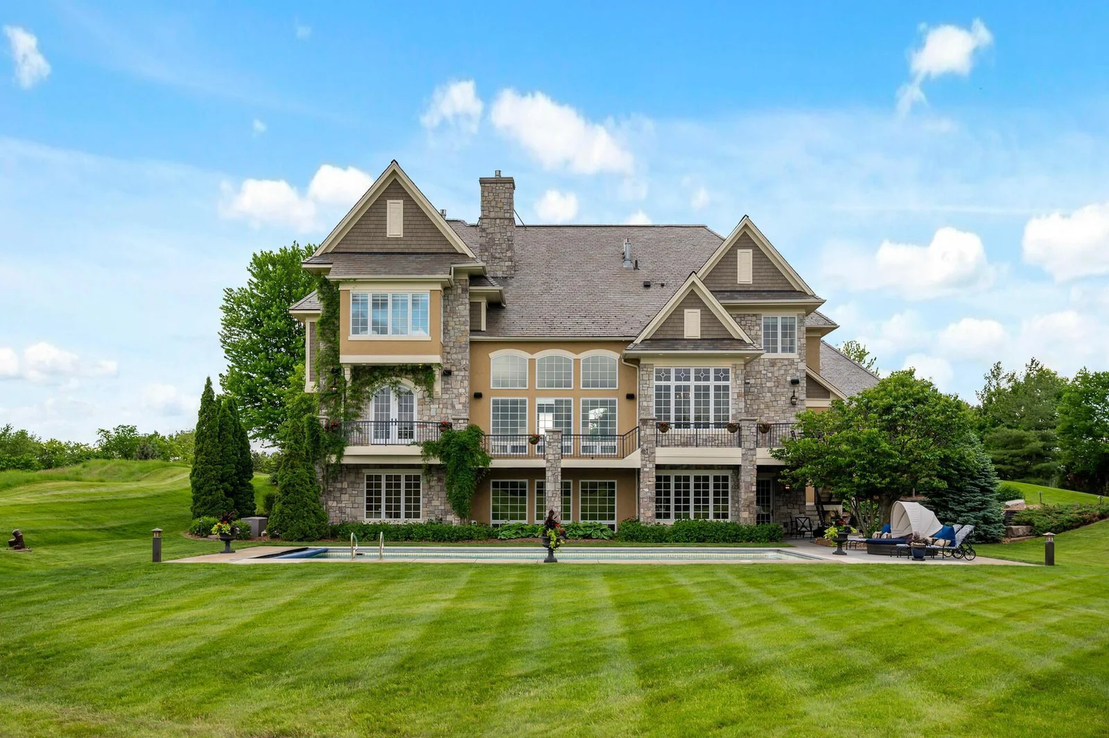 An impressive view of the rear of this Eden Prairie estate, showcasing the expansive grounds and inviting pool area perfect for outdoor living.