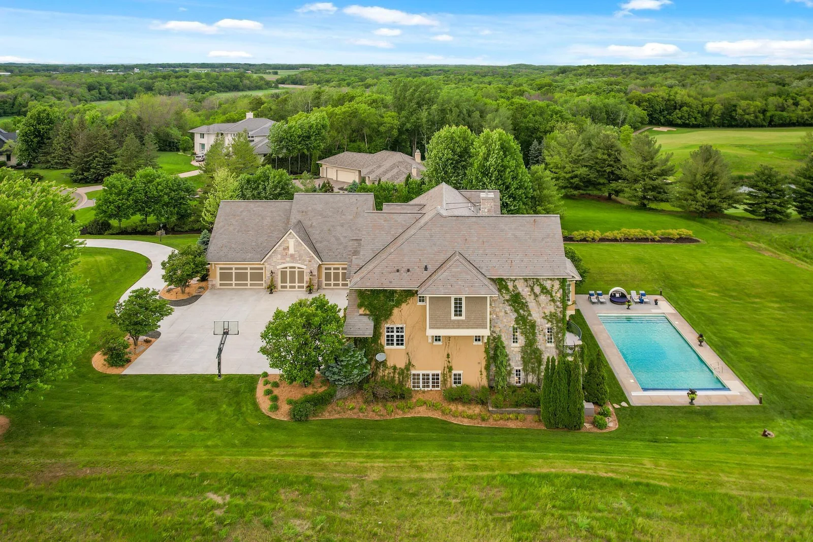A stunning aerial perspective of this beautiful retreat, featuring a sport pool and expansive, private grounds with mature trees.