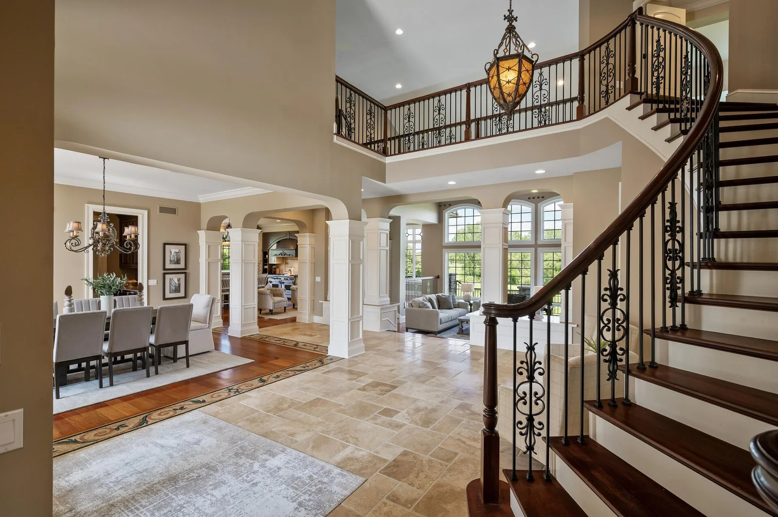 Bathed in natural light, the expansive two-story foyer with its custom vaulted ceiling and ornate iron balusters creates a stunning first impression.