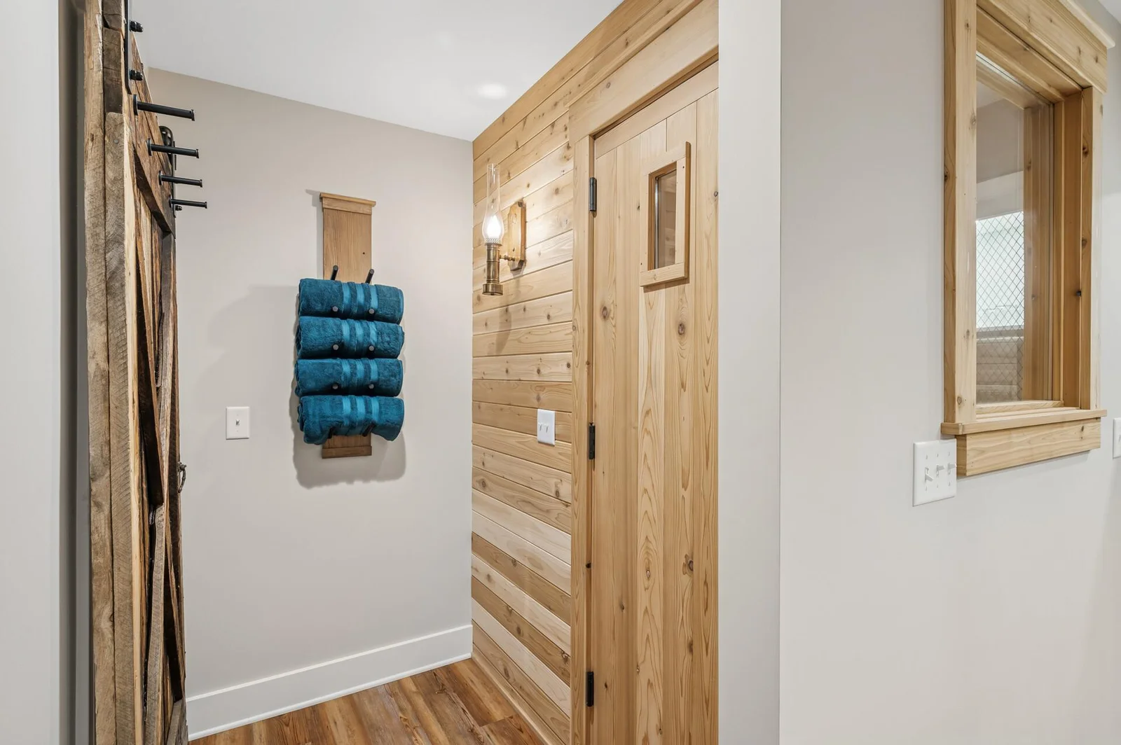 Sauna and adjacent rolling barnwood door that leads to large storage area with utiility sink and 2nd full laundry pair.