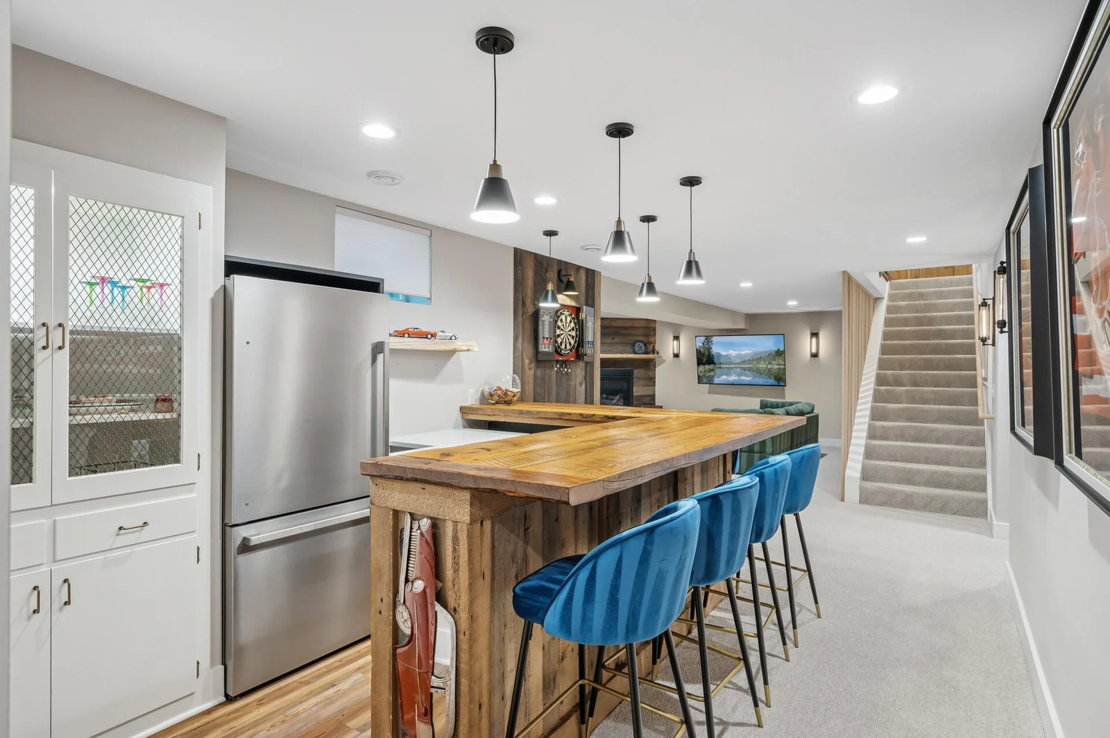 Wet bar in lower level includes full size refrigerator, dishwasher and microwave with continuation of quartz countertops and live edge shelves and bar top.