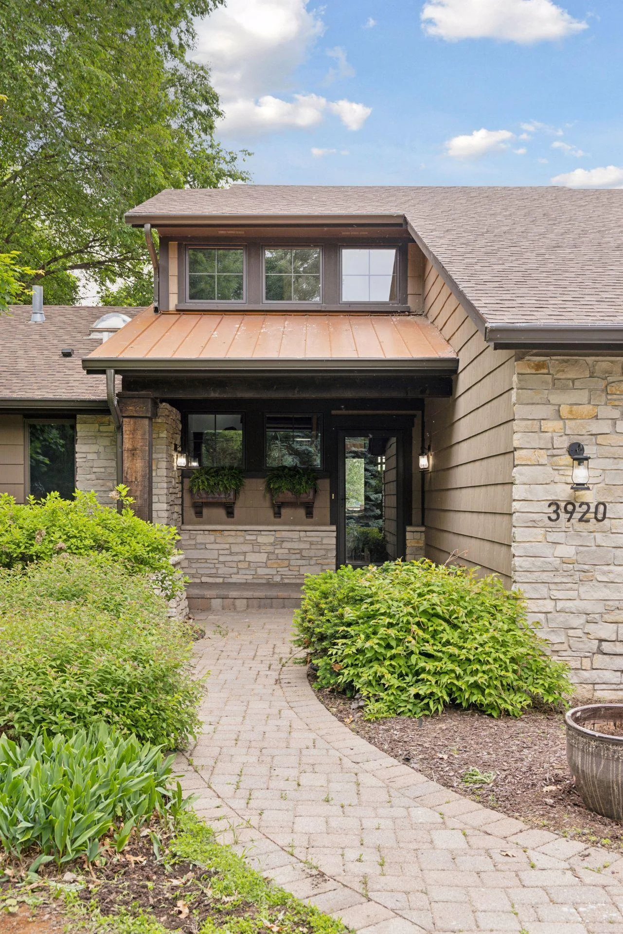 Beautiful covered entry with copper metal roofing and paver path greet you