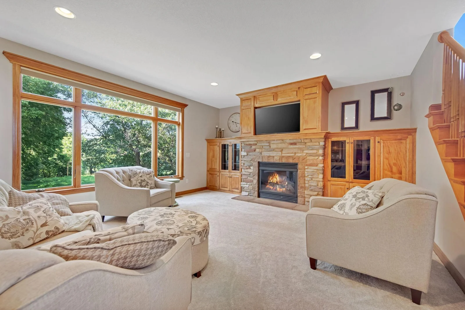 Living room with huge windows that bring in so much natural light. Along with beautiful built-ins and stone gas fireplace!