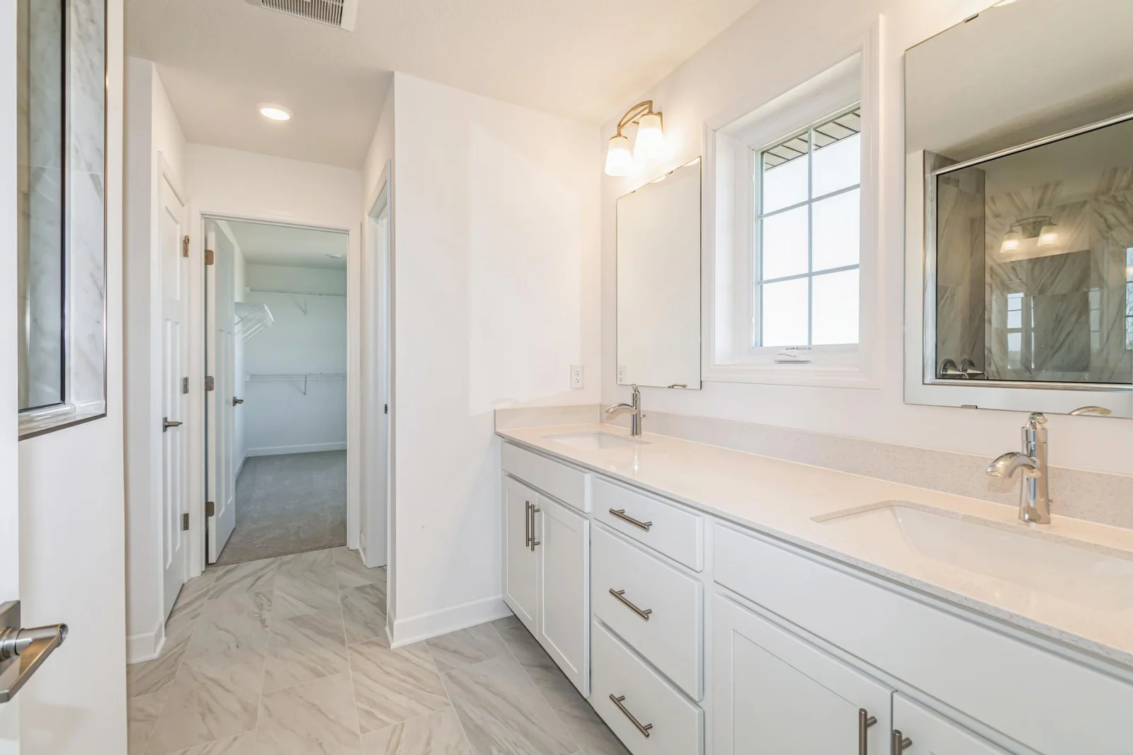 Photo is of the actual home. An extension of the primary bedroom, this spacious bath includes a double-vanity, a soaking tub, and a shower.