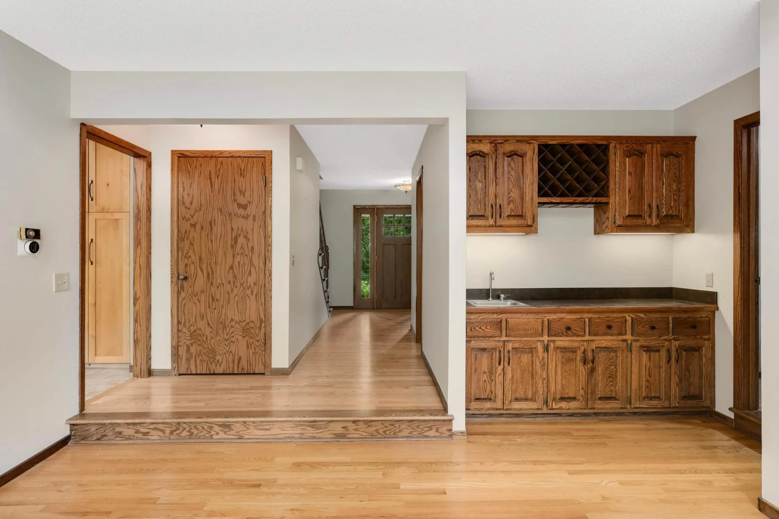 View from living room to foyer and closed door leads to lower level