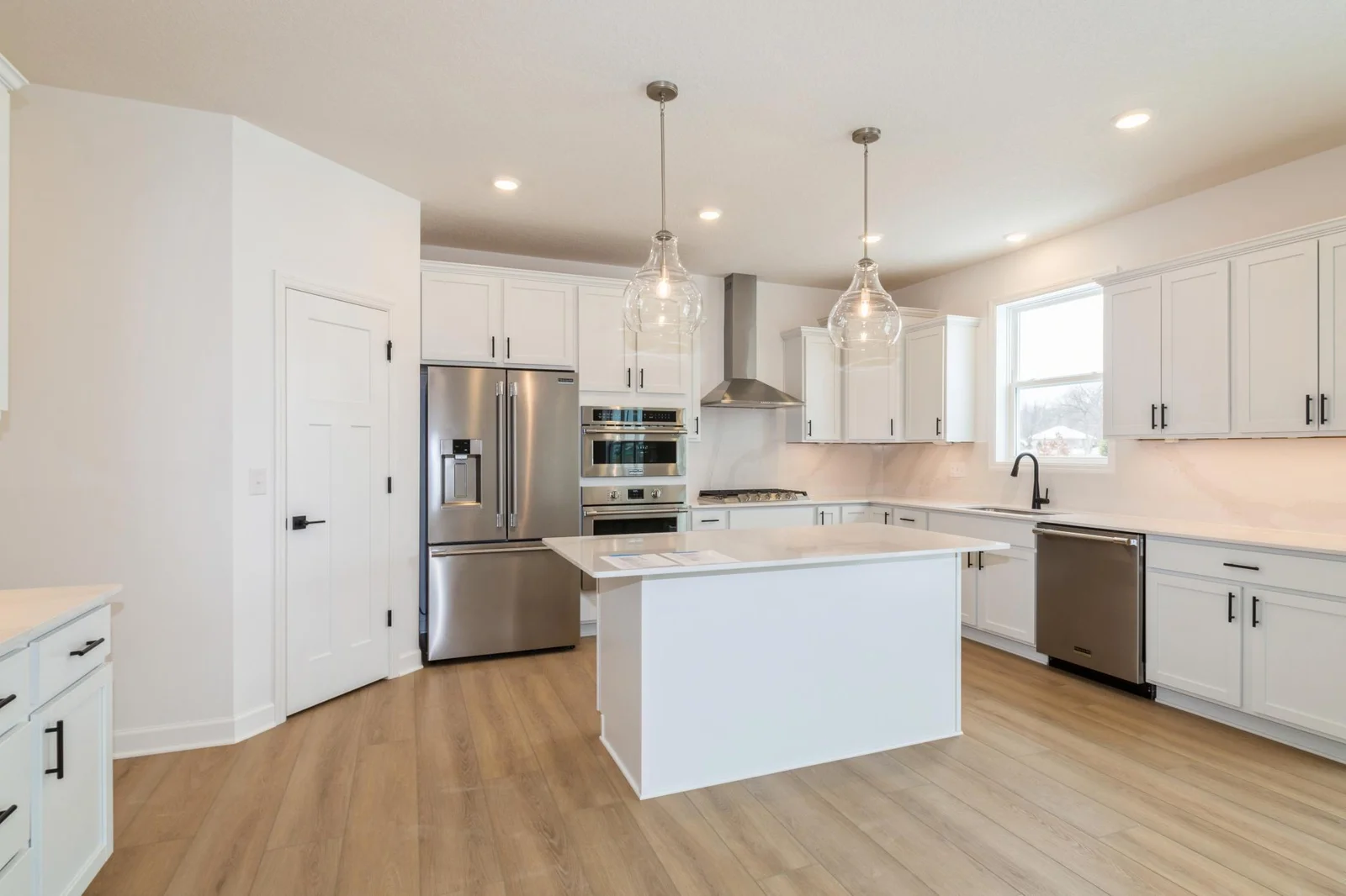 (Photo of a decorated model, actual homes finishes will vary) This spacious gourmet kitchen features a large pantry, quartz countertops, LVP floors, stainless appliances, and more!
