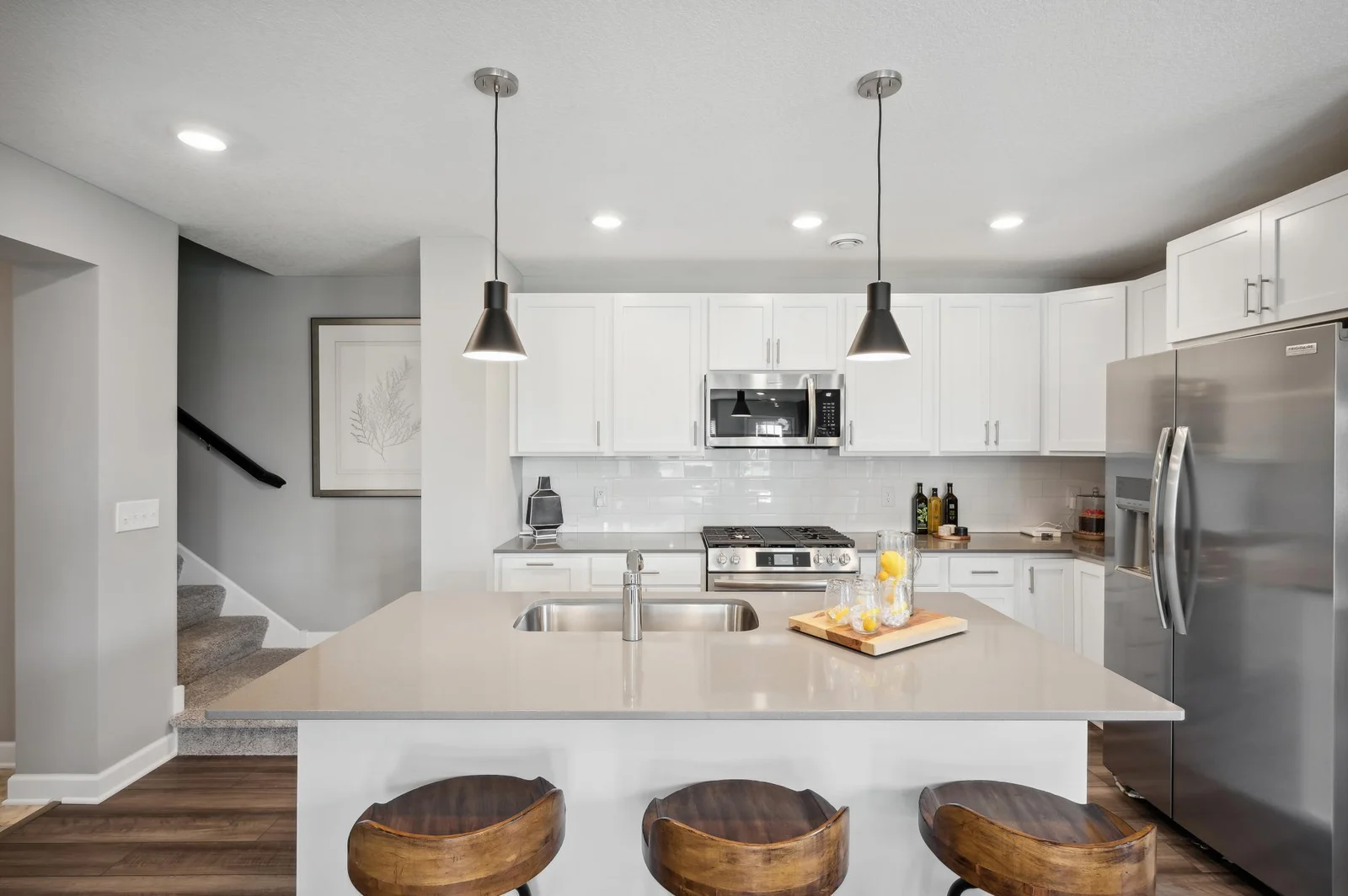 (Photo of decorated model, actual home's finishes vary) Welcome to your new home! This spacious kitchen features a large center island with quartz countertops, under mount sink, recessed lighting, LVP hardwood floors, stainless appliances and more!