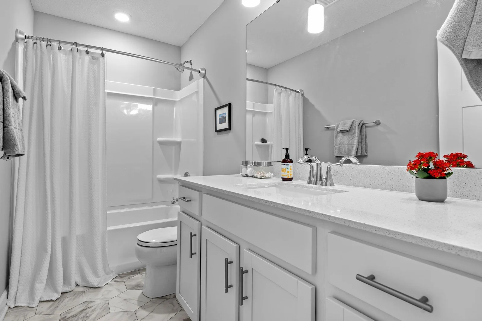 The shared upper level full bathroom, which includes a quartz-topped single vanity, a tub/shower combination, and access to a spacious hallway linen closet for additional storage.