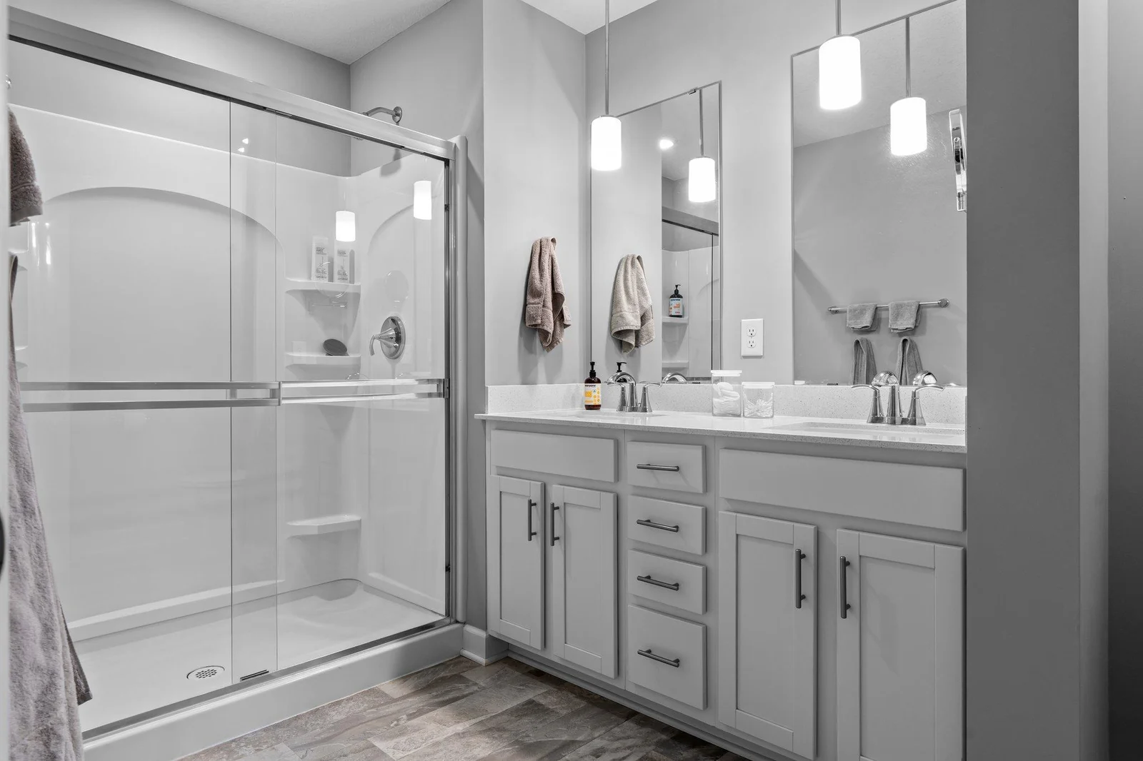 The private en-suite ¾ bathroom includes a double vanity with quartz countertops, stylish pendant lighting, abundant storage, and a walk-in shower.