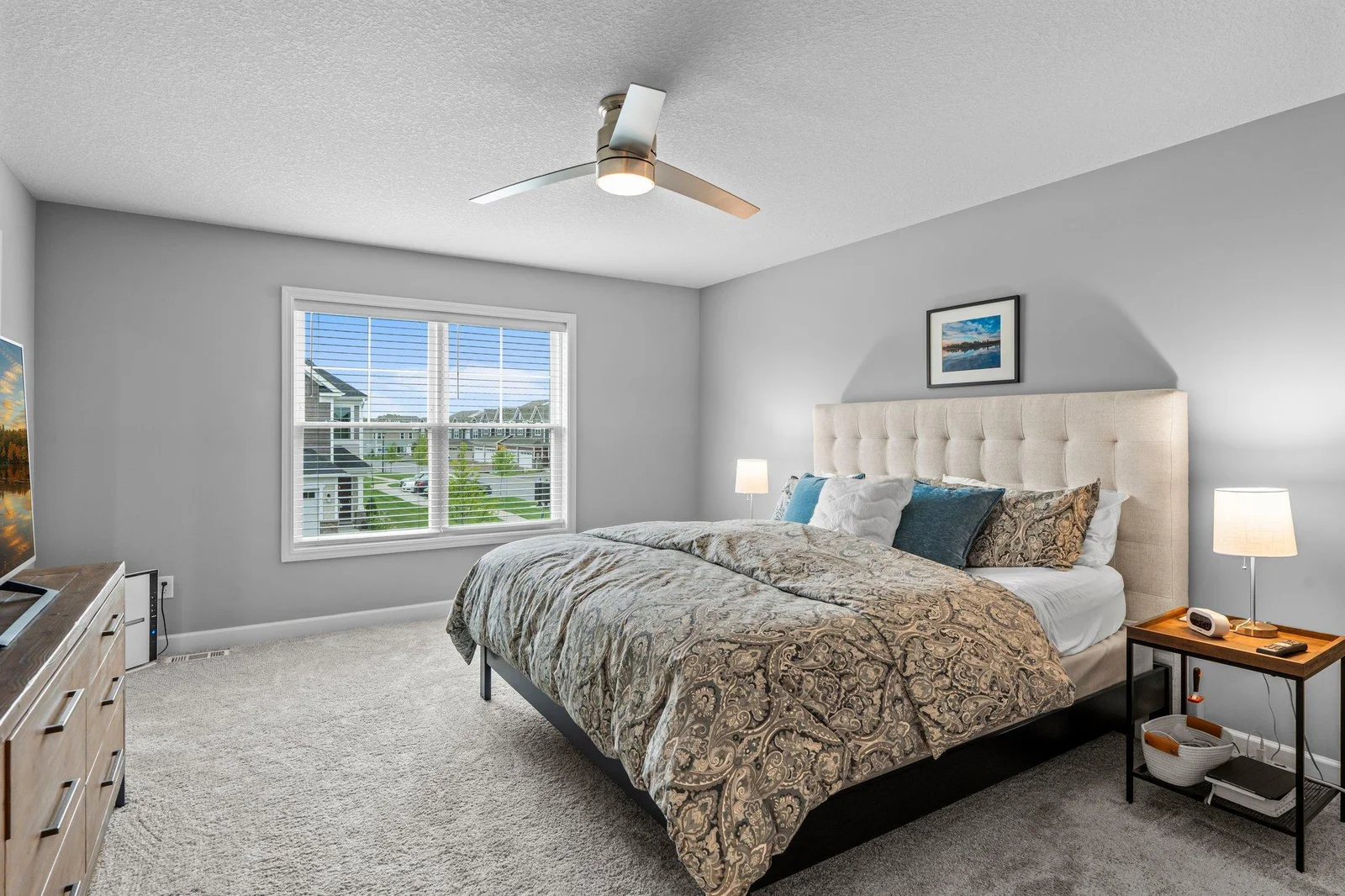 The spacious primary suite features plush carpeting, a ceiling fan for added comfort, and a large front-facing window that fills the room with natural light. A generous 10x5 walk-in closet provides ample space for all your wardrobe needs.