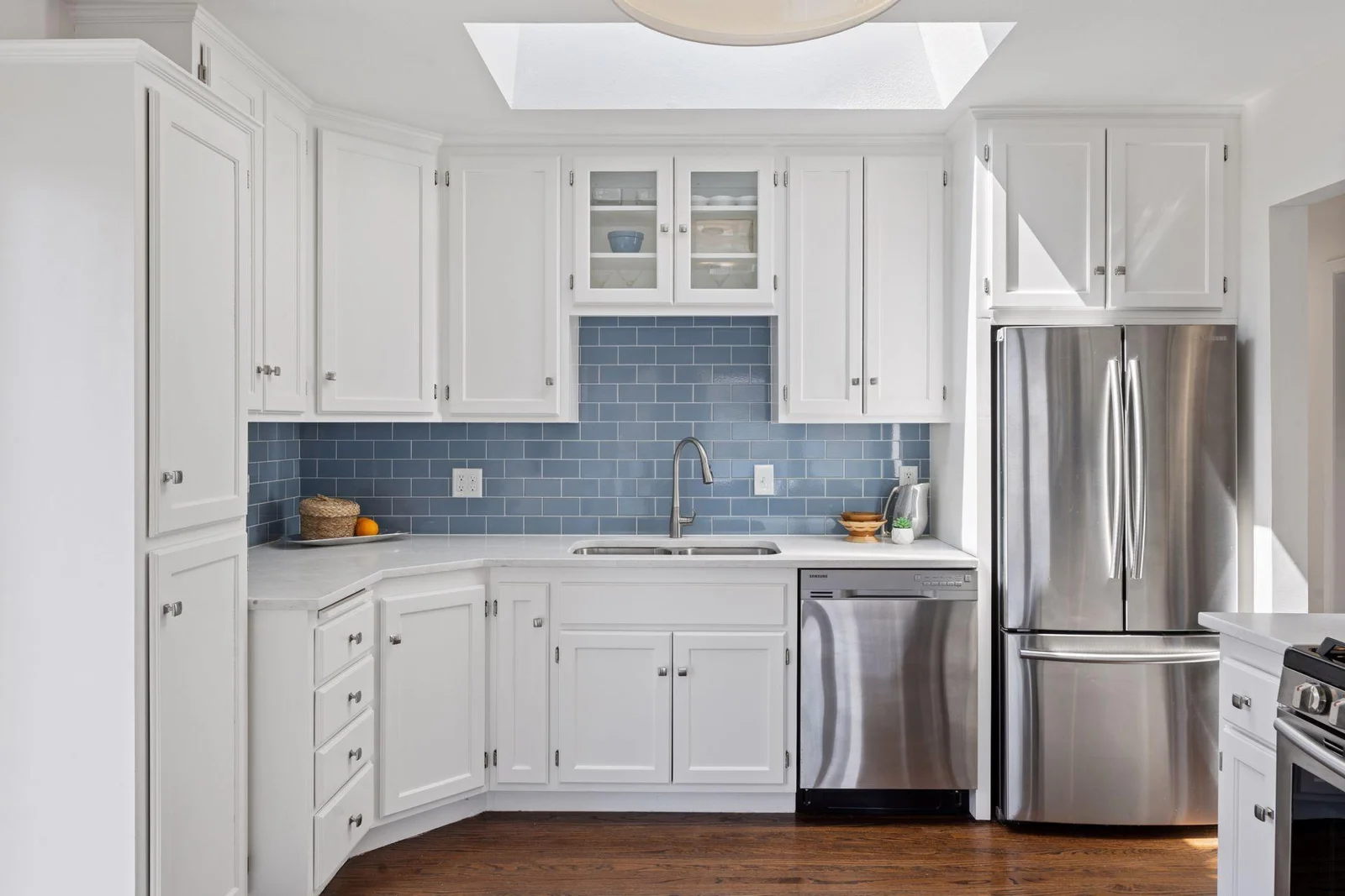 Step into the kitchen featuring sleek stainless steel appliances, beautiful tiling, skylight, and abundant cabinet space