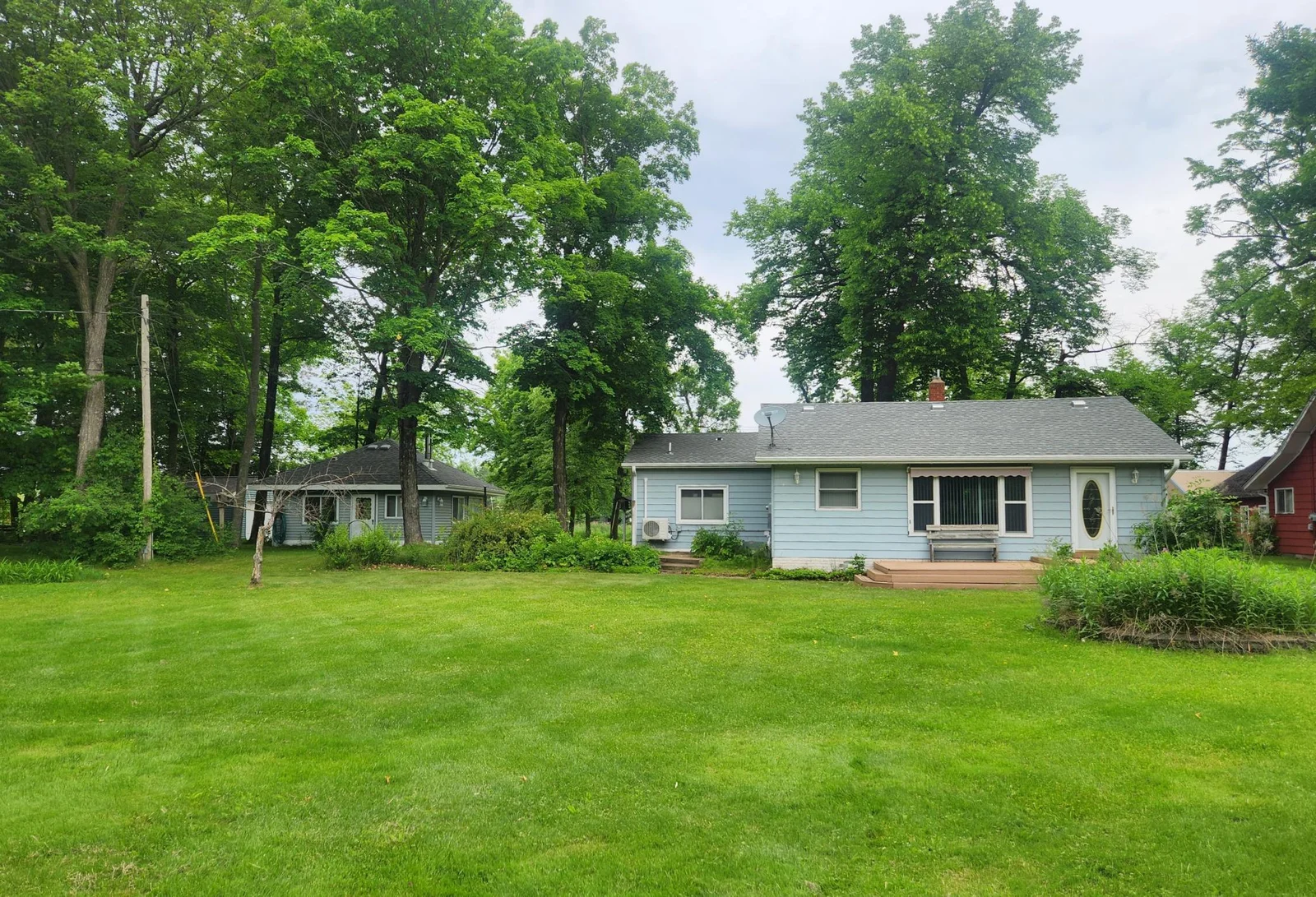 Front view showing guest house to the left (west). This building currently houses the hot tub and wood stove but has been used as a guest house in the past. This building features lake views with ample natural light and a vaulted ceiling.