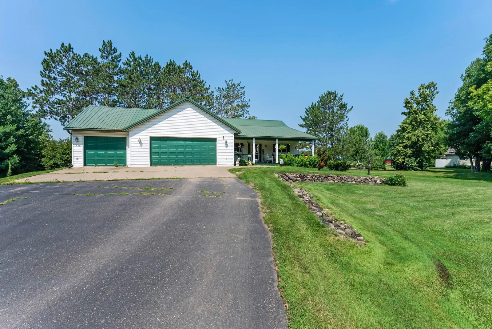 Asphalt and concrete driveway. Well-maintained lawn.