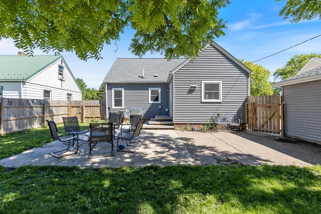 Back view of home and the patio! A latched door offers access to the front of the garage/driveway for easy access around the home while also providing security if you have pets or children to contain!