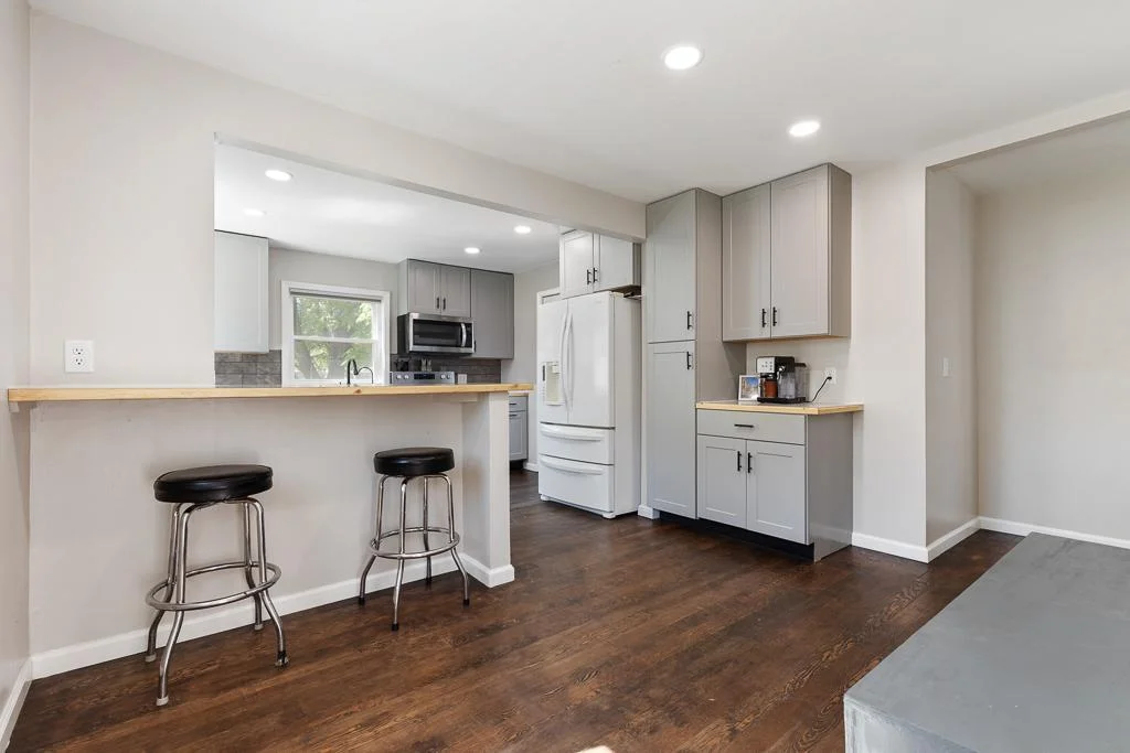 A bar top has been added behind the kitchen island for additional casual seating! Great for when you have company to sit and chat while cooking meals. Note the extended cabinetry providing great storage space and coffee station.