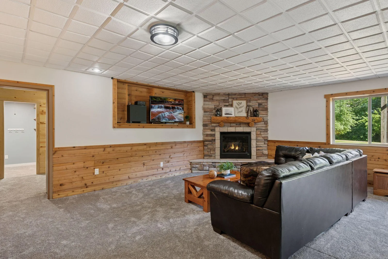Lower level family room with corner stacked stone fireplace