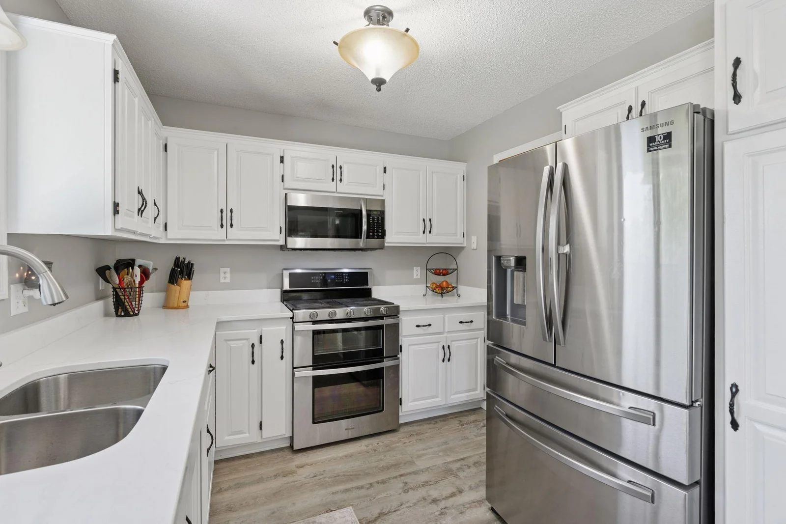 Kitchen features white cabinetry, updated stainless steel appliances and brand new Quartz countertops.