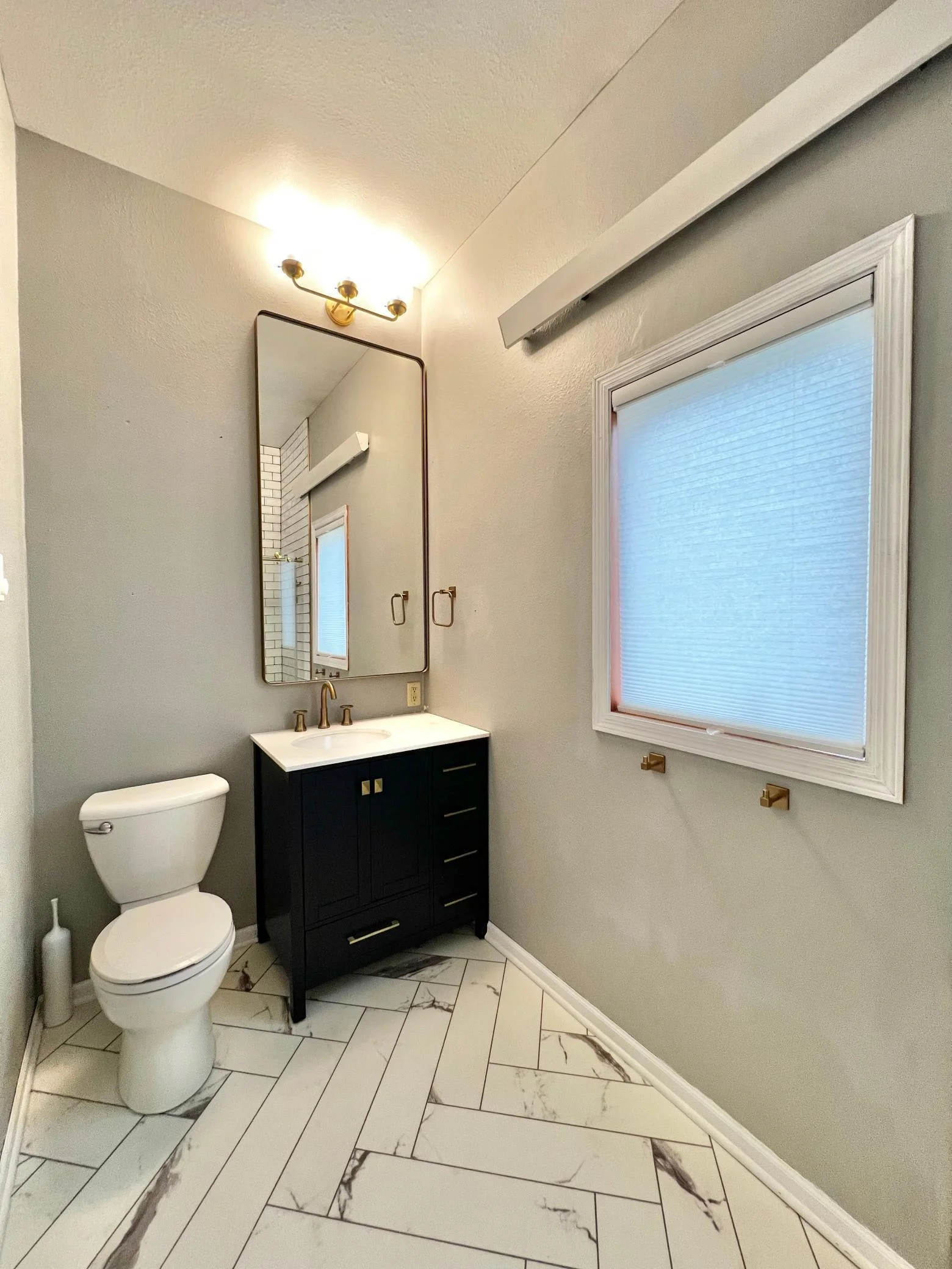 Main Floor Full Bathroom with New LVP Flooring, Navy Blue Vanity with Marble Top, Mirror & Fixtures.