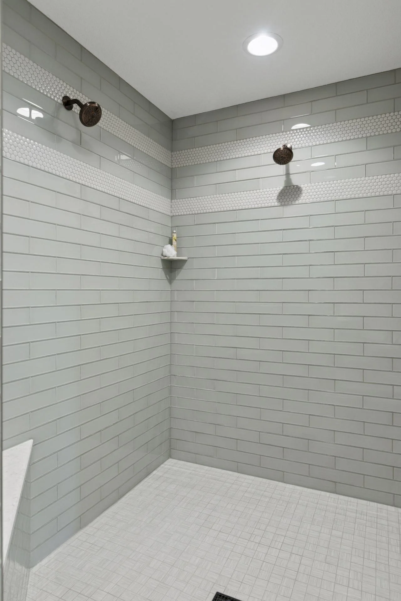 Primary Luxury custom glass tile shower with bench and two niches.
