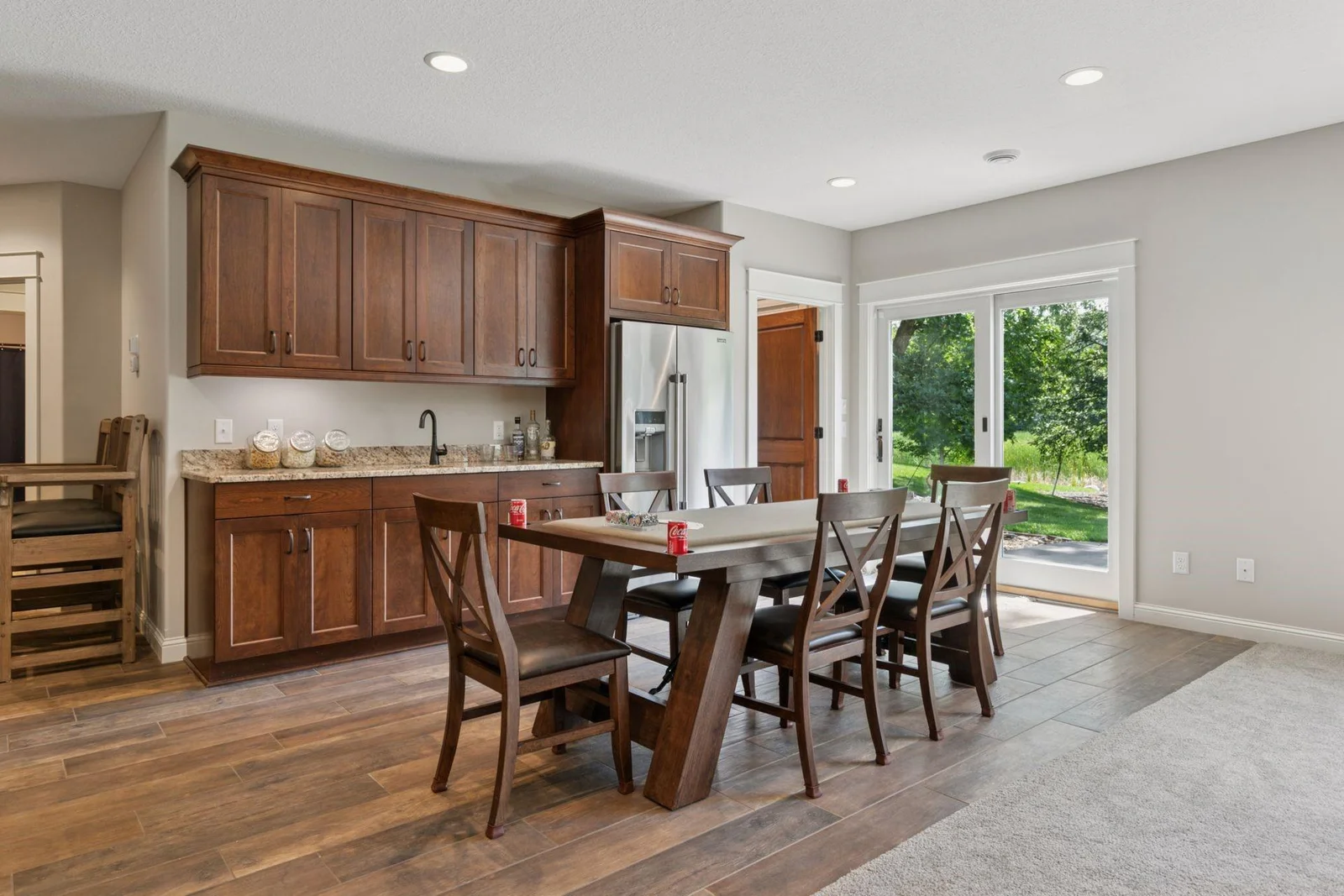 Stunning custom wet bar with full sized fridge, beautiful cabinetry, and slider out to a custom paver patio.